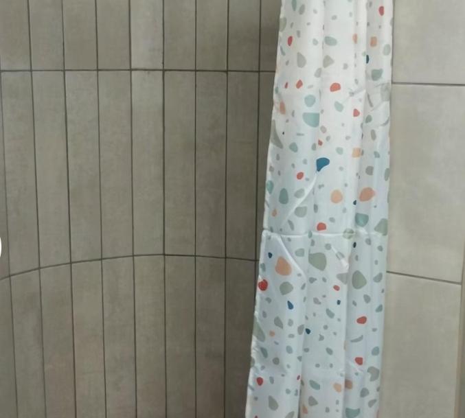 Una cortina de ducha en un baño con suelo de baldosas. en MV Eden Guest Farm, en Bloemfontein