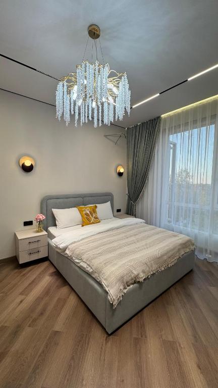 ein Schlafzimmer mit einem großen Bett und einem Kronleuchter in der Unterkunft DeLuXe CLASS HOME in Almaty