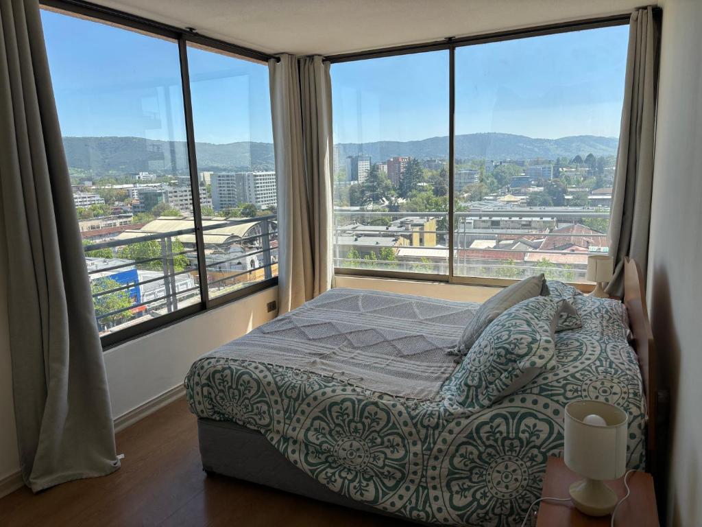 a bedroom with a bed and large windows at Alojamiento Talca centro in Talca