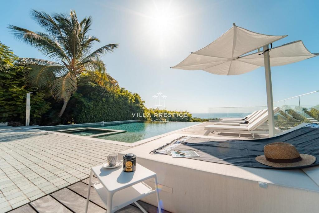 a pool with a chair and an umbrella and a table at La Baie Du Pélican 3 rooms in Mare Gaillard