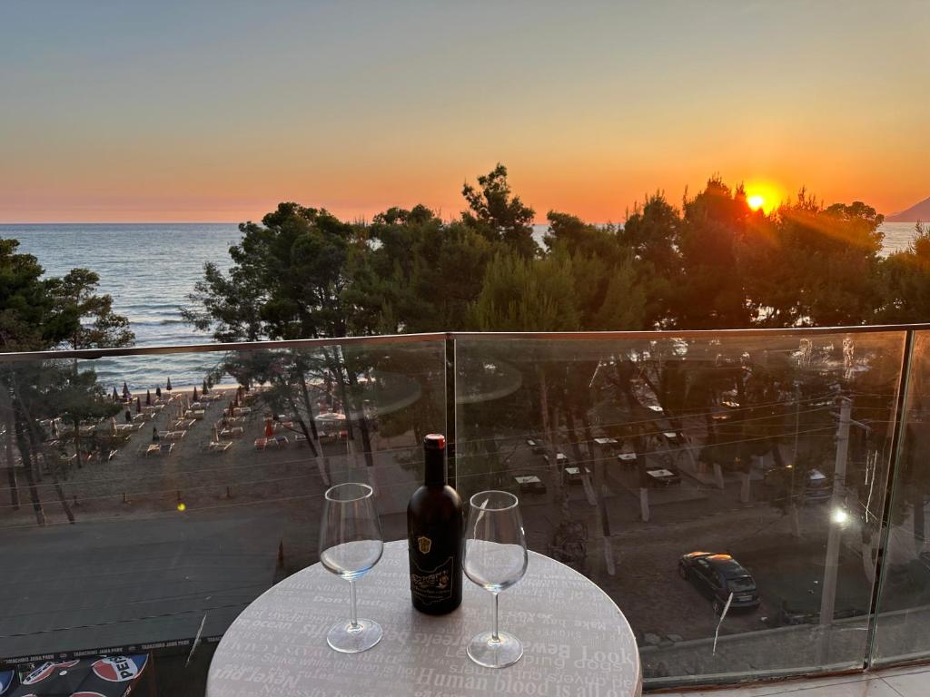 a table with two glasses and a bottle of wine at Sunset Luxury Apartment Shengjin in Lezhë