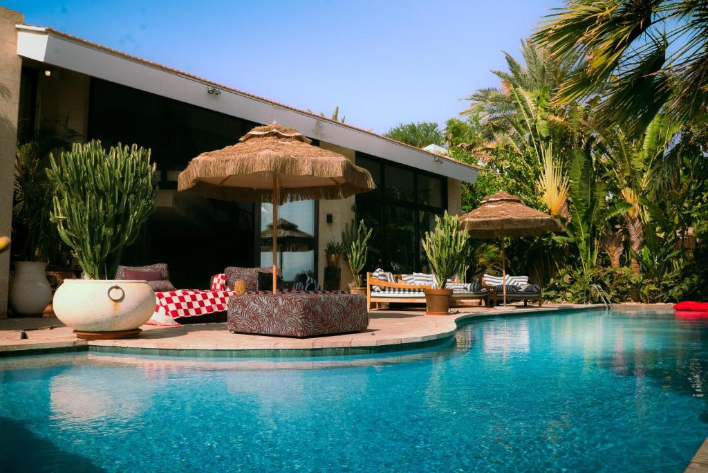 a swimming pool with chairs and an umbrella next to a building at Villa Balfour in Eilat