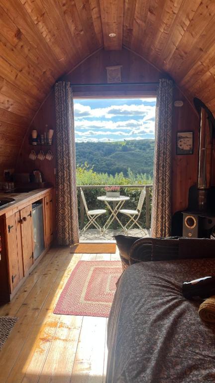 马汉莱斯Hillside hideaway - Hendre-Aur Pod的卧室设有大窗户,享有桌子的景色