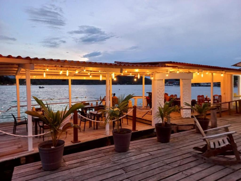 a deck with a table and chairs on the water at Hotel Cocotal in Isla Grande