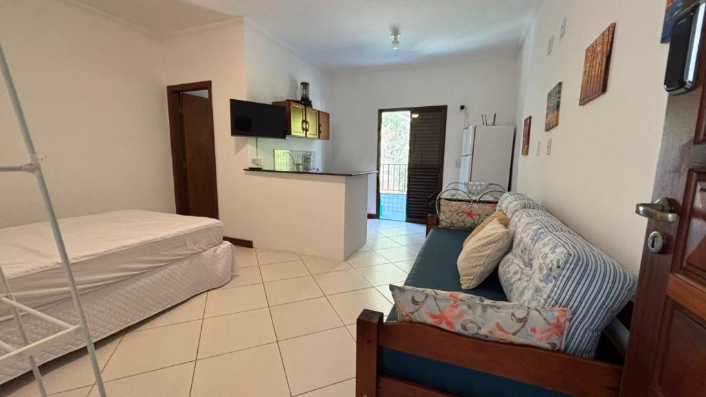 a room with a bed and a couch and a kitchen at Surf House Mar Brasil in Ubatuba