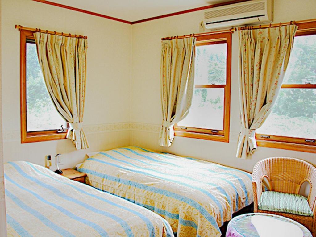 a bedroom with two beds and a chair and windows at Minamiuonuma - Hotel - Vacation STAY 23091v in Myōgasawa