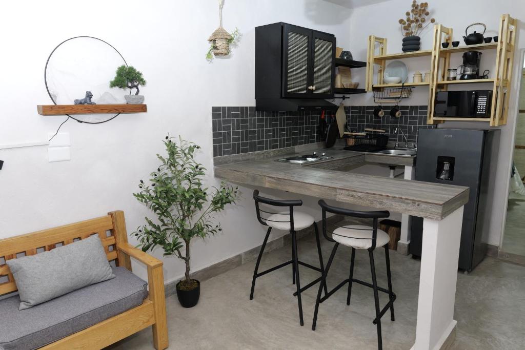 a kitchen with a counter and bar stools at Departamento Refugio Sereno cerca de la UAS y nuevo hospital General in Culiacán