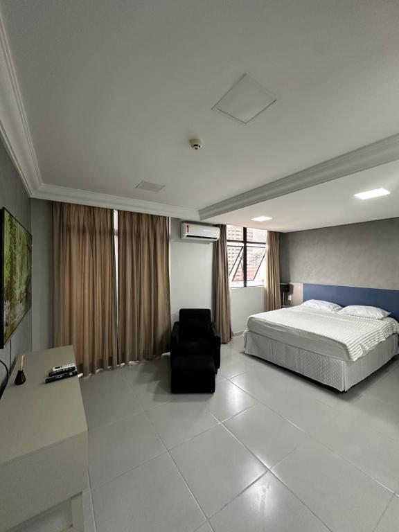 a bedroom with a bed and a black chair at Flat Aconchegante no Millenium Hotel in Manaus