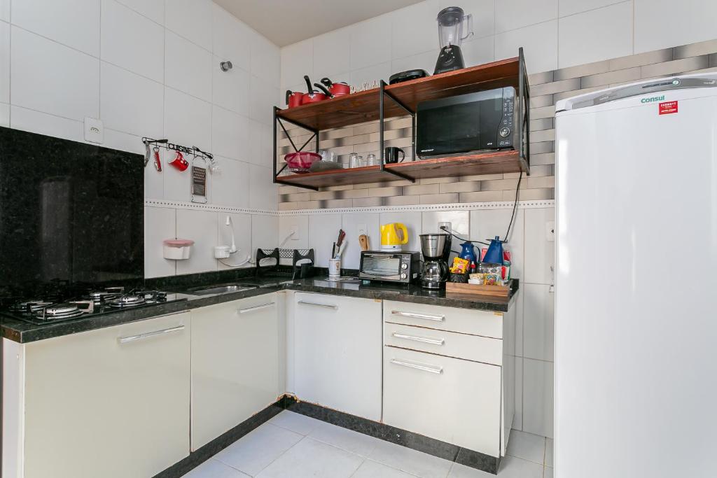 a kitchen with white cabinets and a refrigerator at Casa perto do centro e da Udesc Cefid in Florianópolis