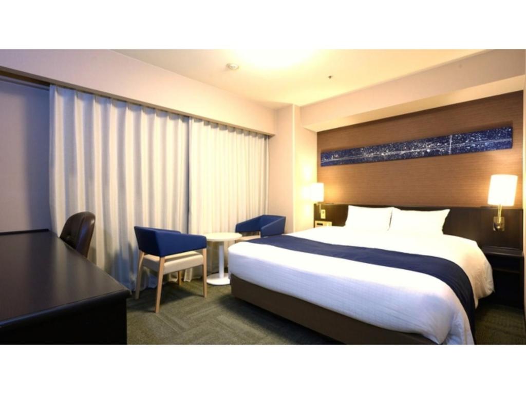 a hotel room with a bed and a table and chairs at Smile Hotel Premium Kanazawa Higashiguchi Ekimae - Vacation STAY 65344v in Housai