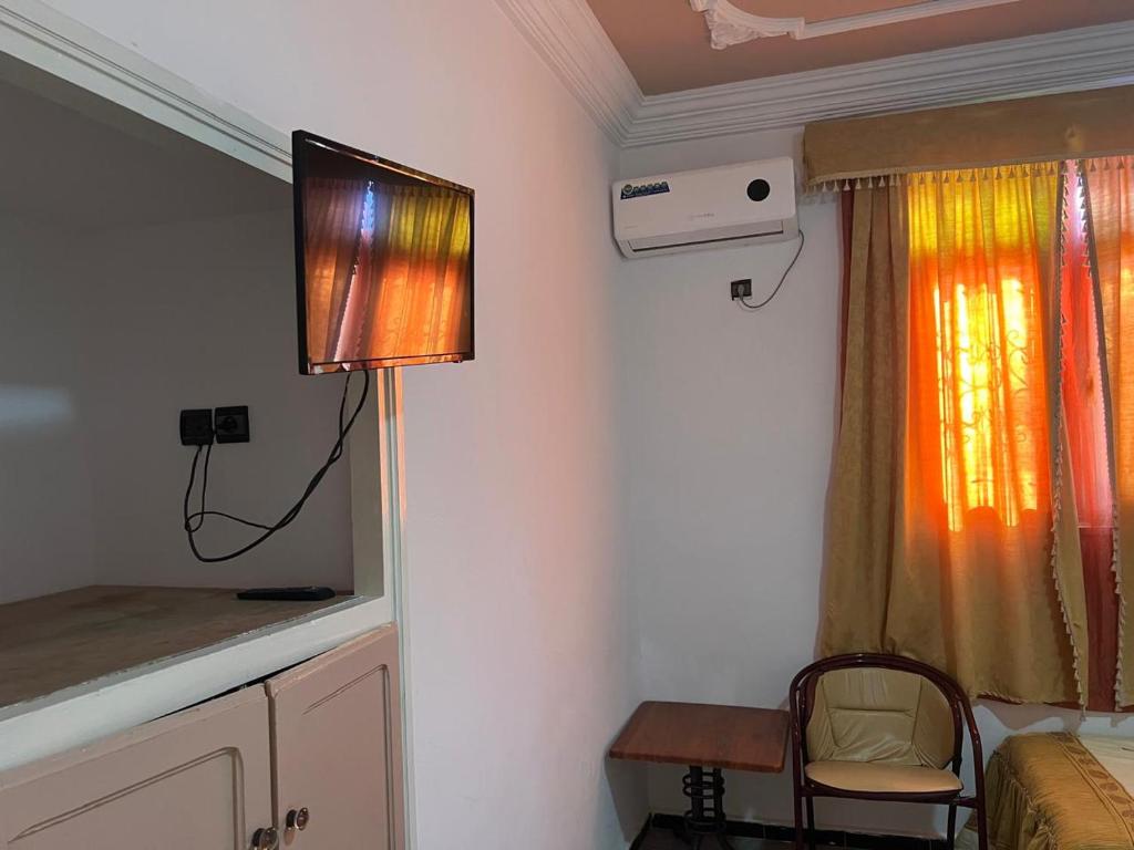 Cette chambre comprend une télévision, un lit et une table. dans l'établissement COMPLEXE TOURISTIQUE ARTIZANAL bab sahara, à Oulad Akkou