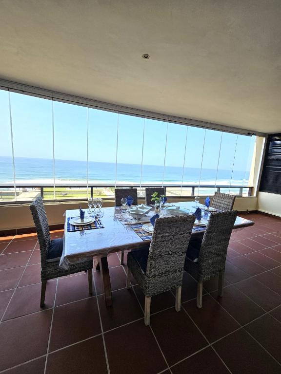 a dining room with a table and chairs and the ocean at Maya's Beachfront Haven in Westbrook