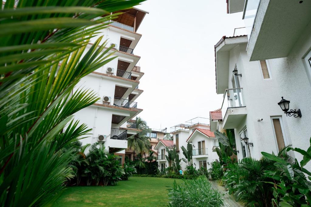 a row of white buildings with a green yard at The Tanisi Resorts & Pool Villas, Candolim in Candolim