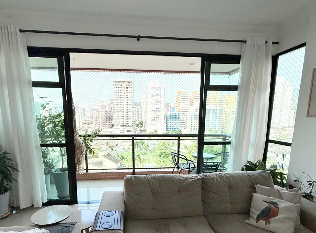 a living room with a couch and a large window at Lar e Mar PG in Praia Grande