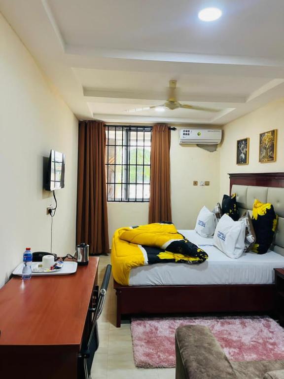 Pharrell Luxury Hotel的卧室里有一张书桌和一张铺着黄色床单的床