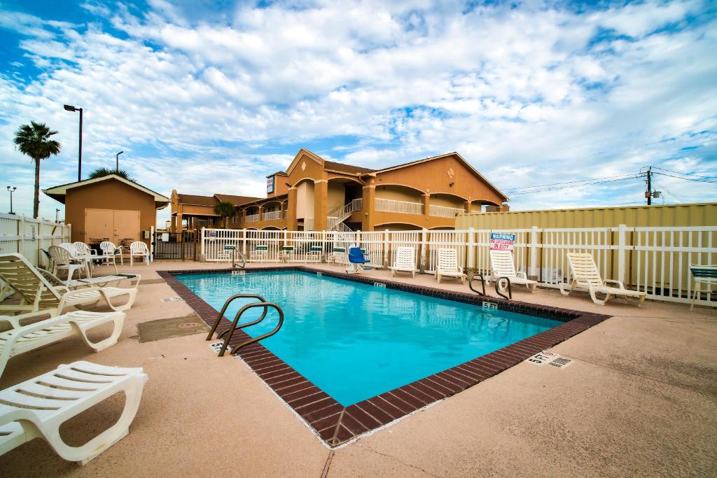 a swimming pool with lounge chairs and a building at Island Inn By OYO Galveston Beach, TX in Galveston