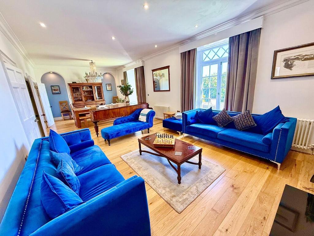 a living room with blue couches and a table at A Grand Georgian Grade II Manor House with Views in Laugharne in Laugharne
