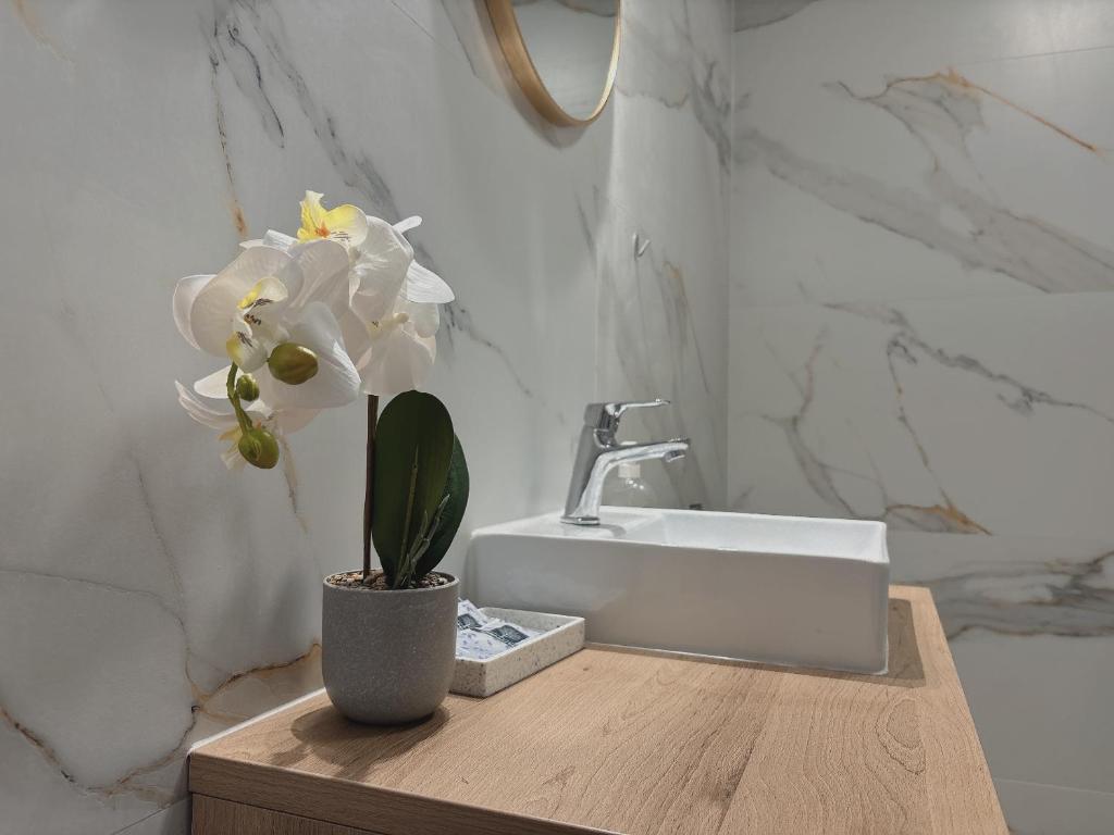 a bathroom with a sink and a vase of flowers at Mikołowska 9 pokój in Gliwice