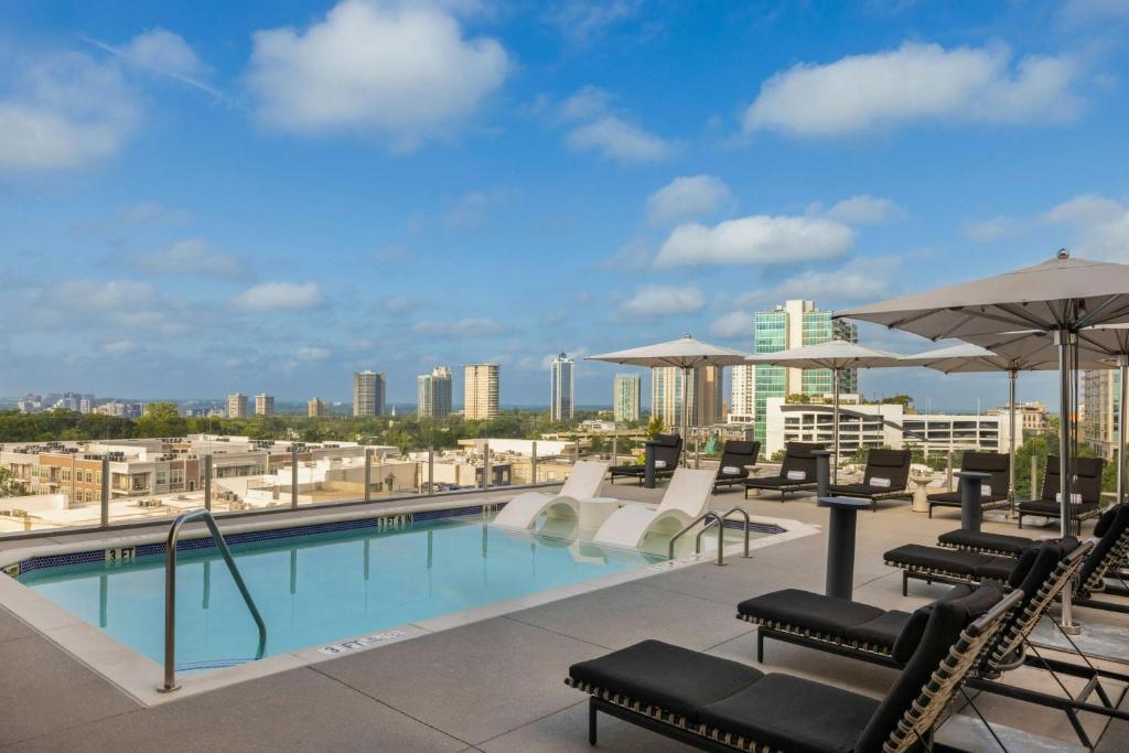 a pool with chairs and umbrellas on top of a building at The Tess, Autograph Collection in Atlanta