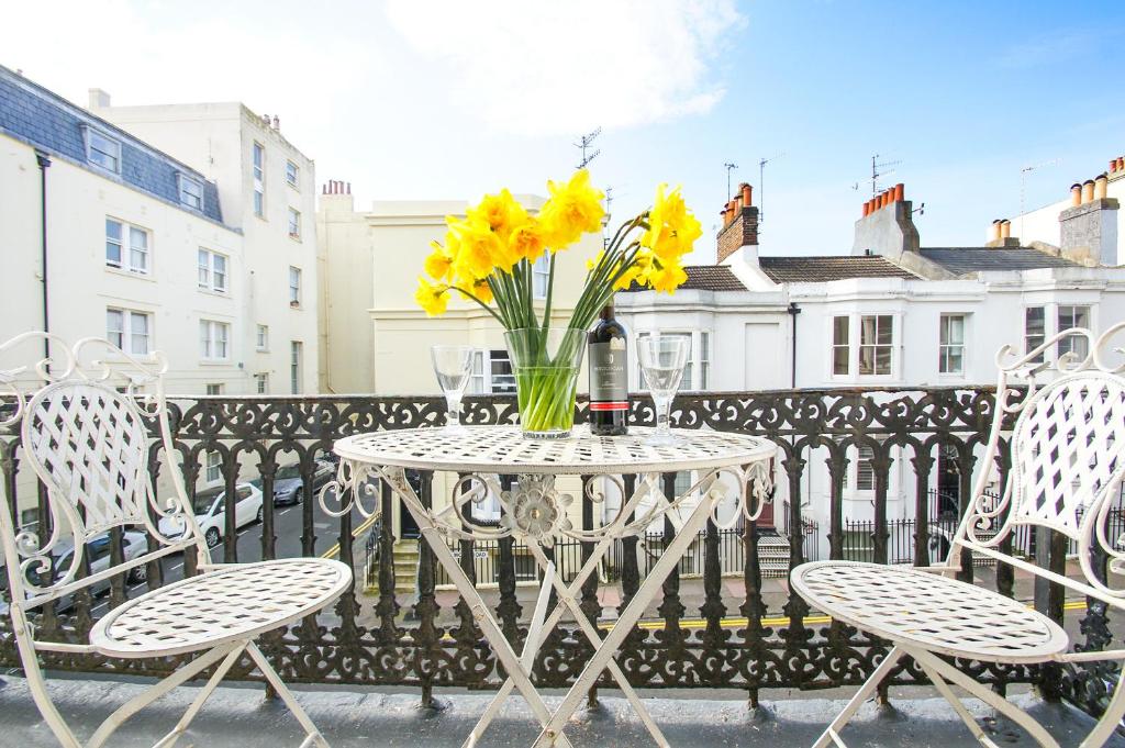 a table with a vase of yellow flowers on a balcony at Sillwood Balcony Apartment - Central - by Brighton Holiday Lets in Brighton & Hove