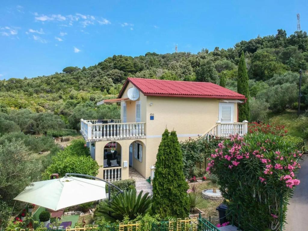 una casa amarilla con techo rojo en Apartmani Kolić, en Rab