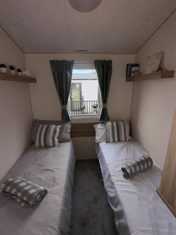 two beds in a small room with a window at Two Bedroom Caravan on 7 Lakes Country Park in Crowle