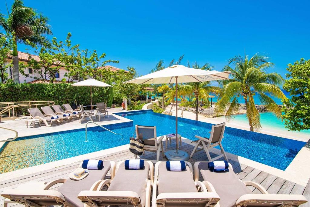 - une piscine avec des chaises longues et des parasols à côté d'un complexe dans l'établissement Casa Luna 5 - Limited-Time Deal for Families on This Spacious Beach Villa, à George Town