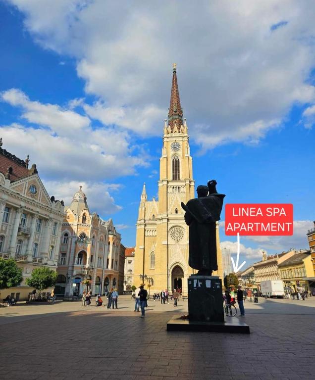 a statue in front of a building with a clock tower at Linea Spa Apartment in Novi Sad