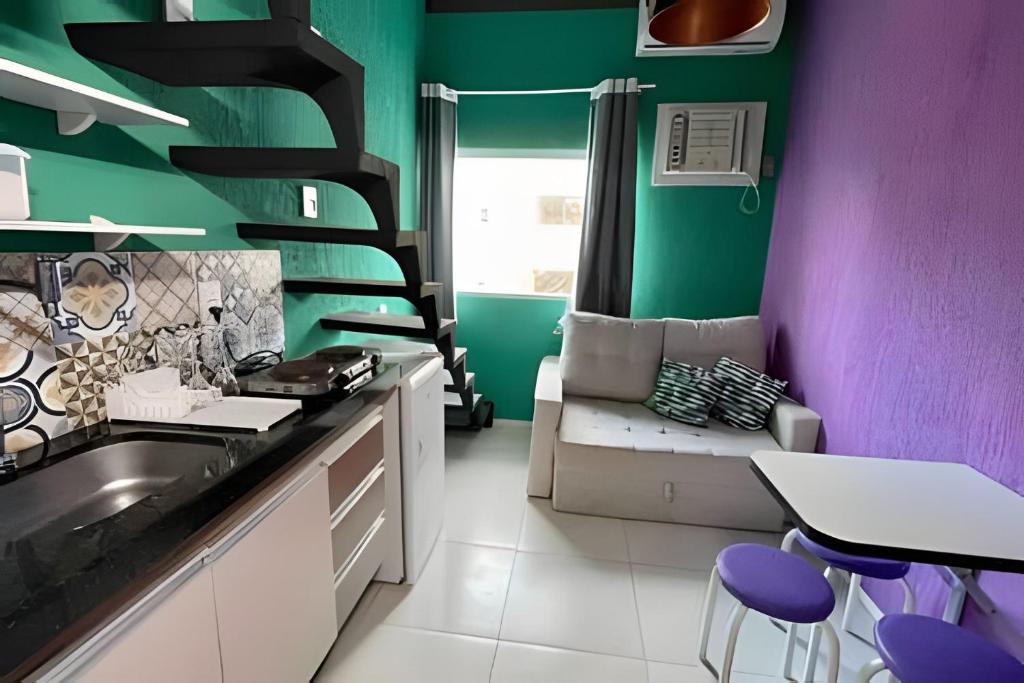 a kitchen with purple and green walls and a couch at Flat em Maracaípe -Praia vizinha Porto de Galinhas in Porto De Galinhas