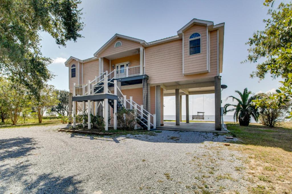 a house with a staircase in front of it at Private Beach and Views! Stilted Ocean Springs Home in Gulf Park Estates