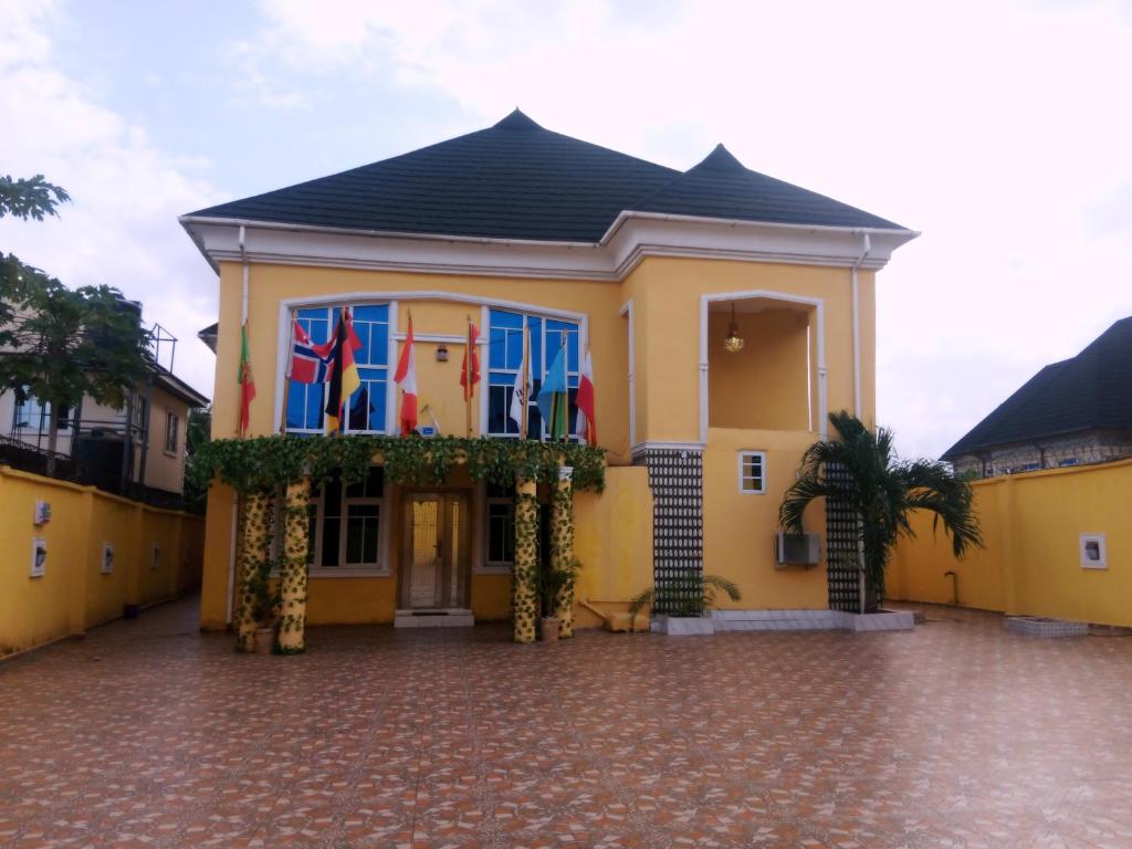 una casa amarilla con banderas en un balcón en Grandsheffield 8 hotel, en Mama