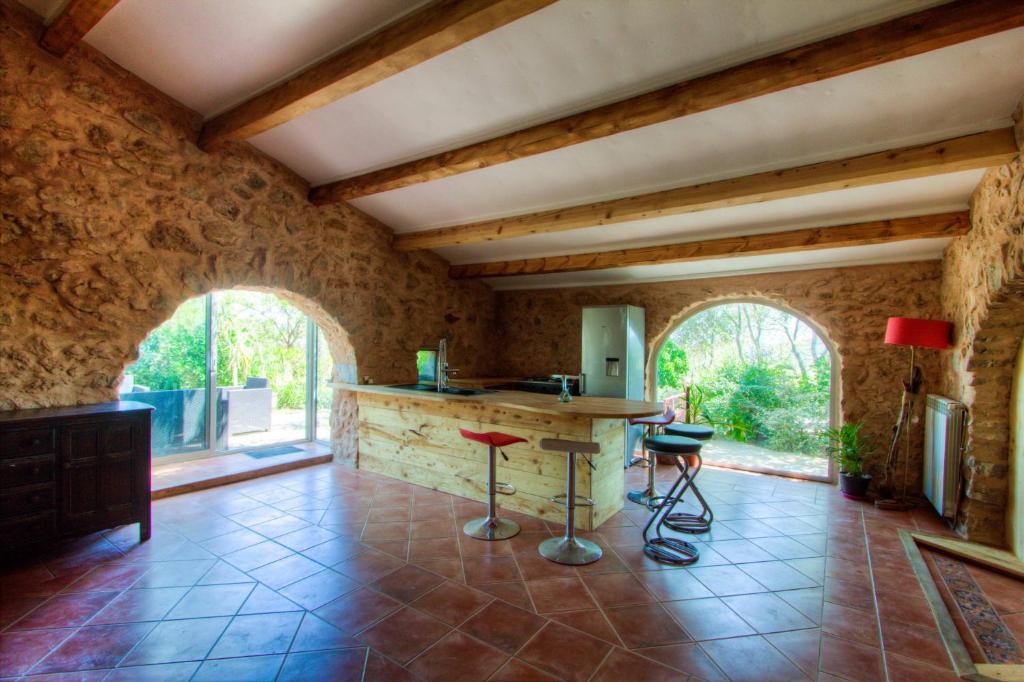 a kitchen with stone walls and a counter with stools at La bergerie du chateau de Fitou in Fitou