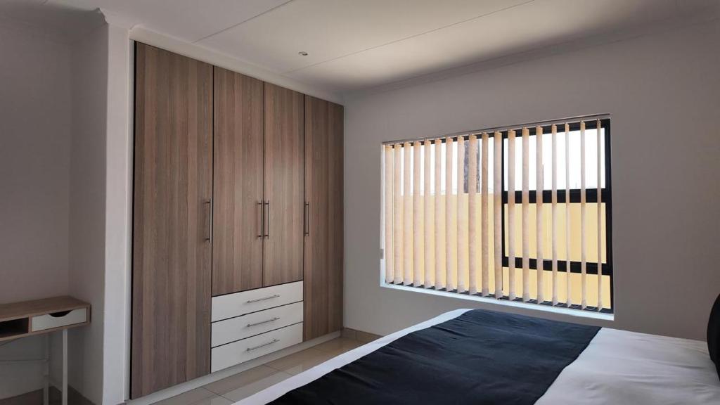 a bedroom with a bed and a large window at The Pebbles in Mahikeng