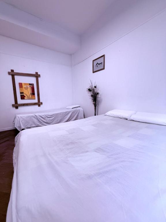a white bedroom with two beds and a picture on the wall at housecheconquista in Buenos Aires