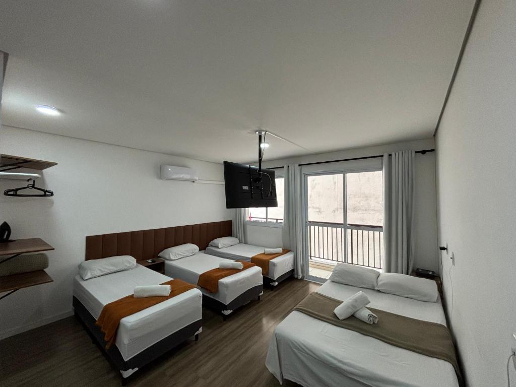 Cette chambre comprend 4 lits et une télévision murale. dans l'établissement SeuLar o conforto de um Lar em Qualquer Lugar, à São Paulo