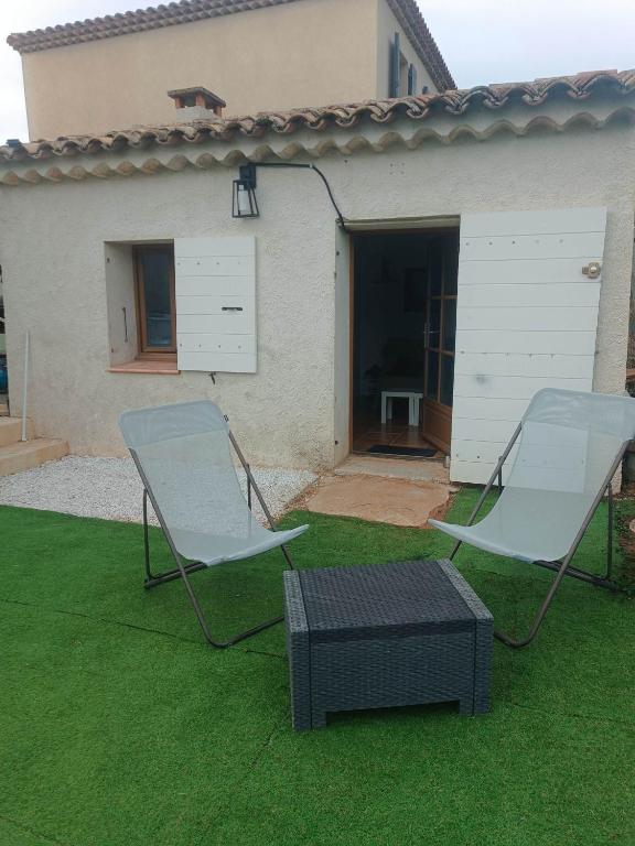 two chairs and a table in front of a house at Le Cabanon des Collines in Signes