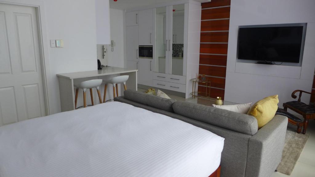 a bedroom with a bed and a kitchen with a tv at ITowers Luxury Apartment 2 in Gaborone