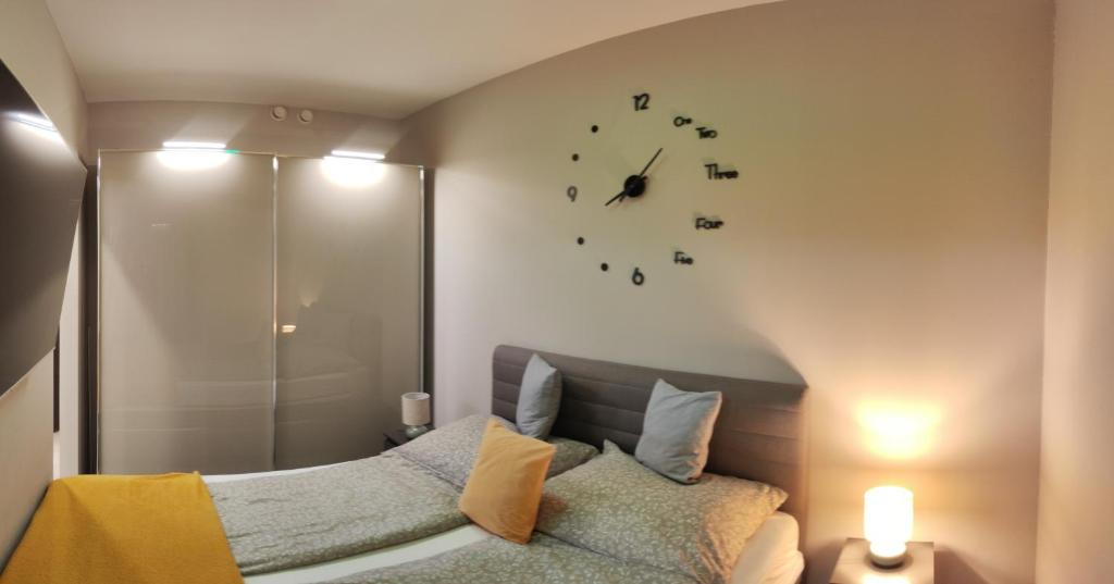 Un dormitorio con una cama y un reloj en la pared. en Oasis Residence, en Hajdúszoboszló