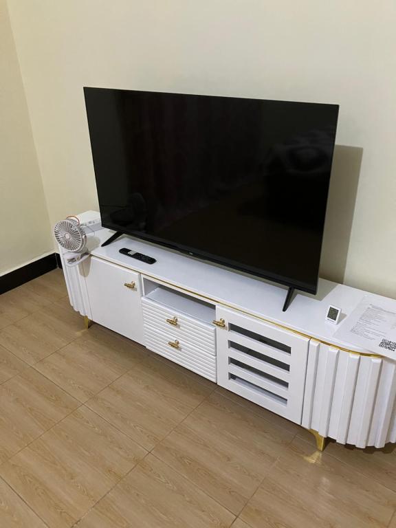 a large flat screen tv on a white entertainment center at Friendly House in Arusha