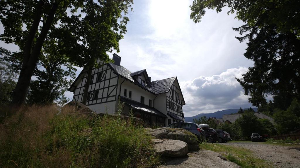 una casa en blanco y negro con coches aparcados frente a ella en Willa Uroboros, en Szklarska Poręba