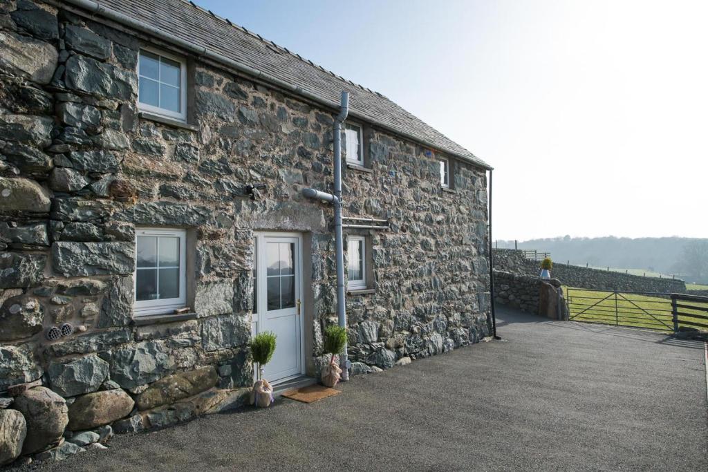 a stone building with a white door and windows at Cefn-Isaf in Llanbedr