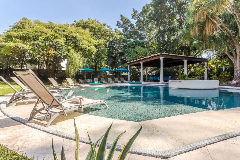 a swimming pool with chairs and a gazebo at Casona de Elefantes in Cuernavaca