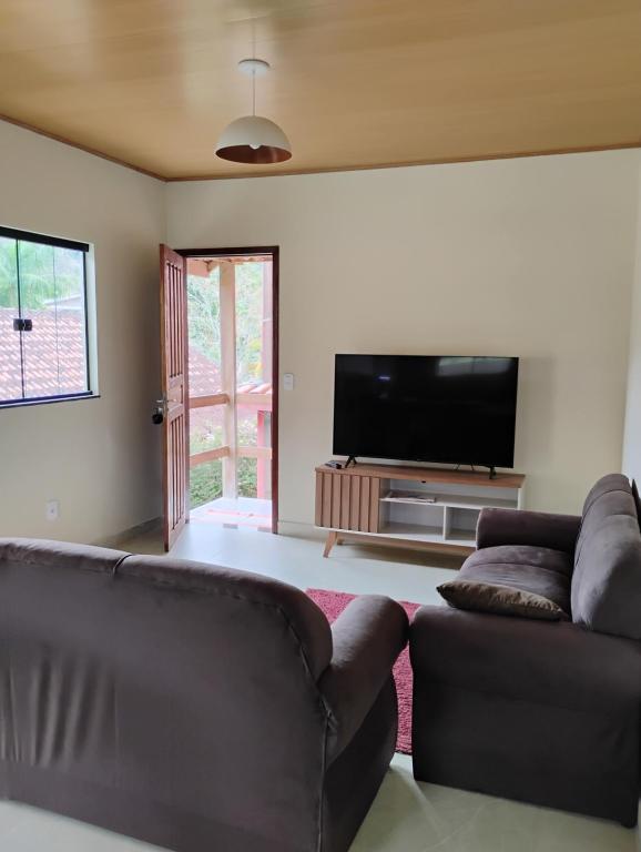 a living room with two couches and a flat screen tv at Casa Vale dos Peões Lumiar 3 in Nova Friburgo