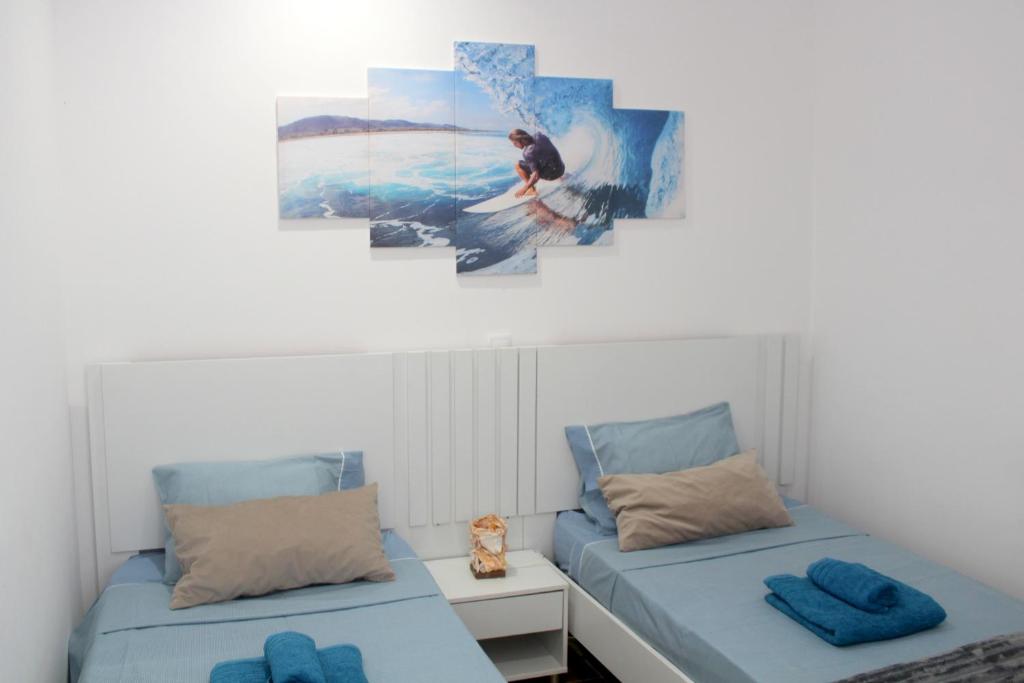 a bedroom with two beds and a painting on the wall at My Boavista 2 in Sal Rei