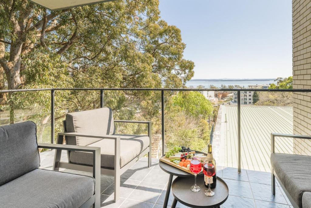 a balcony with a couch and a table with drinks on it at Sunset Towers 11, 25 Donald St - stunning water views, air con, Wi-Fi and Linen provided in Nelson Bay