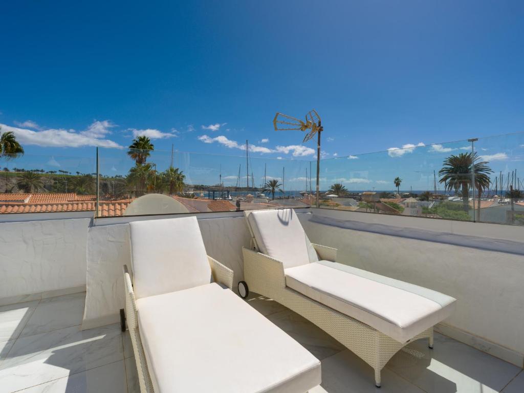 a pair of white chairs sitting on a balcony at FaroQuilla Suites Pasito Blanco in Pasito Blanco