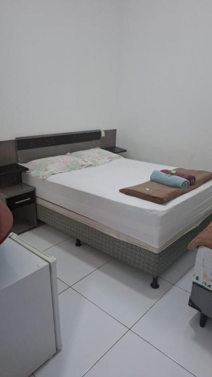 a bed sitting on top of a white floor at Pousadinha Litoral in Mucuri