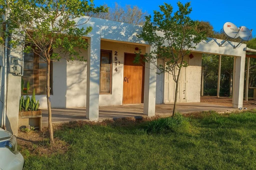 a small white house with a wooden door at Casa en Lago Merin Uruguay in Lago Merin