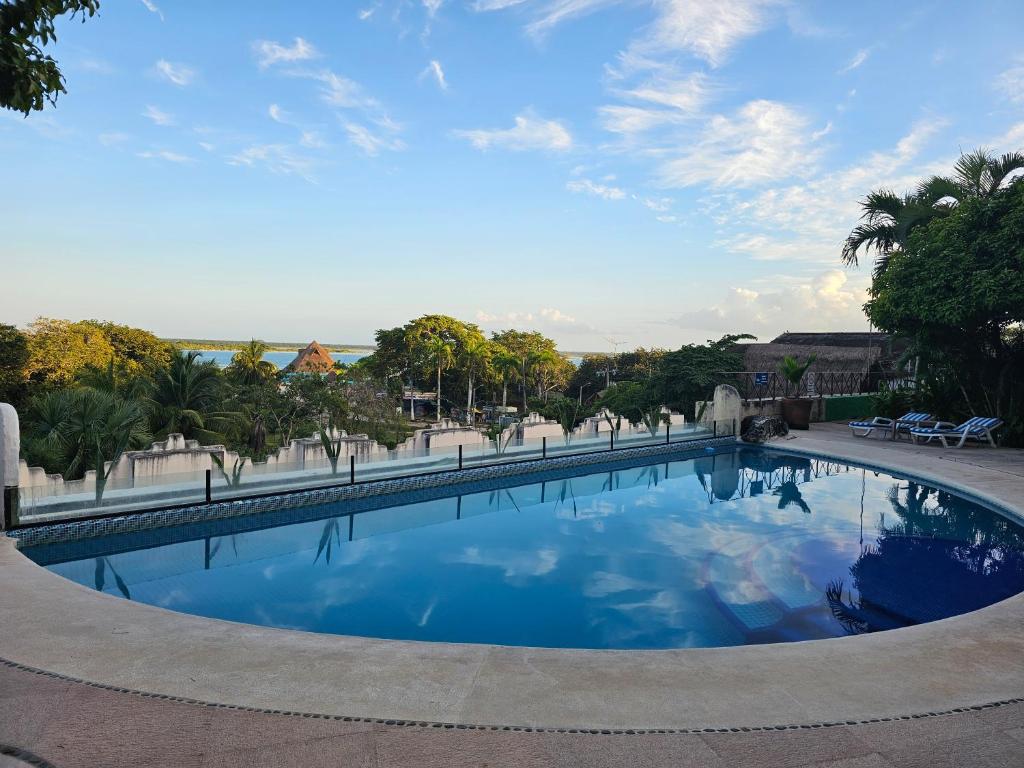 ein großer Pool mit blauem Wasser und Palmen in der Unterkunft Viajero Bacalar Hostel in Bacalar