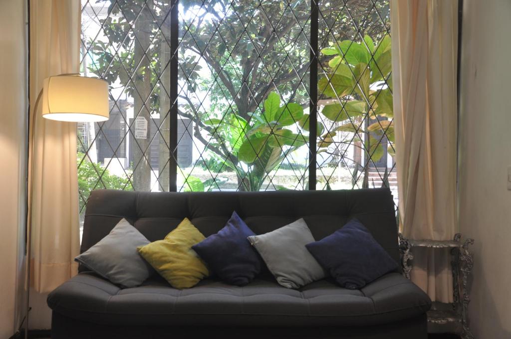 a couch with pillows sitting in front of a window at Laureles, casa completa y amplia para grupos grandes in Medellín